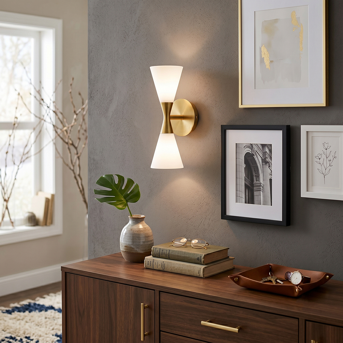 Mid-Century Modern Glass Wall Sconce 4 Elegant brass hourglass wall lamp mounted on a grey wall above a wooden entryway console table.
